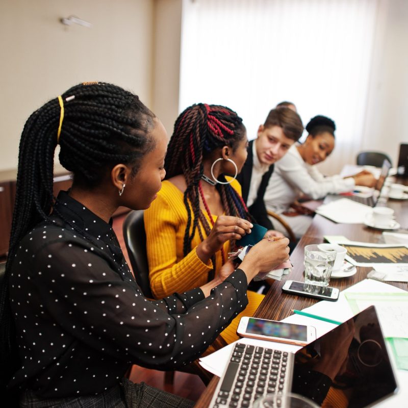 Multiracial business team addressing meeting around boardroom table.